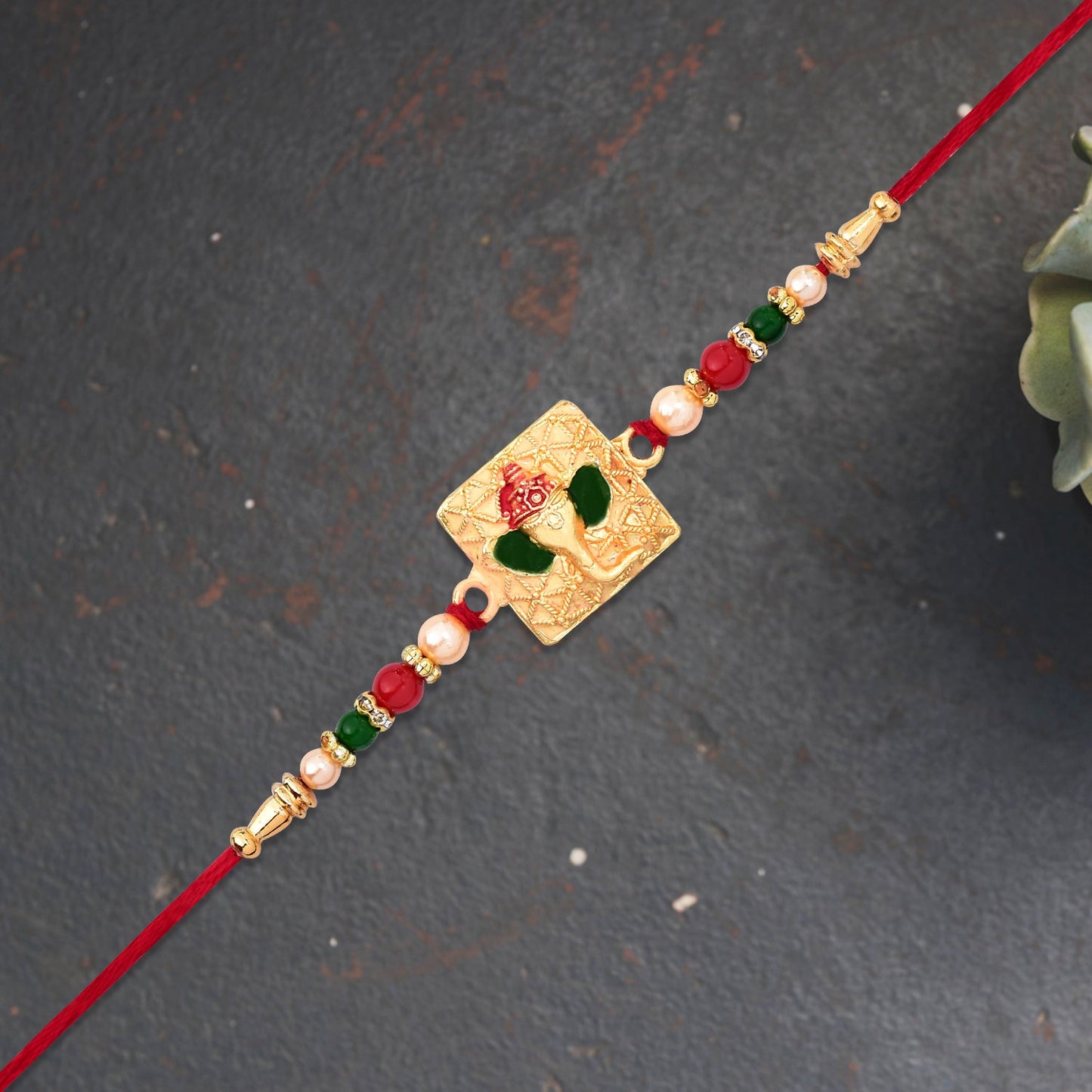 Golden Ganpati Rakhi with Red-Green Beads and Enamel Detailing