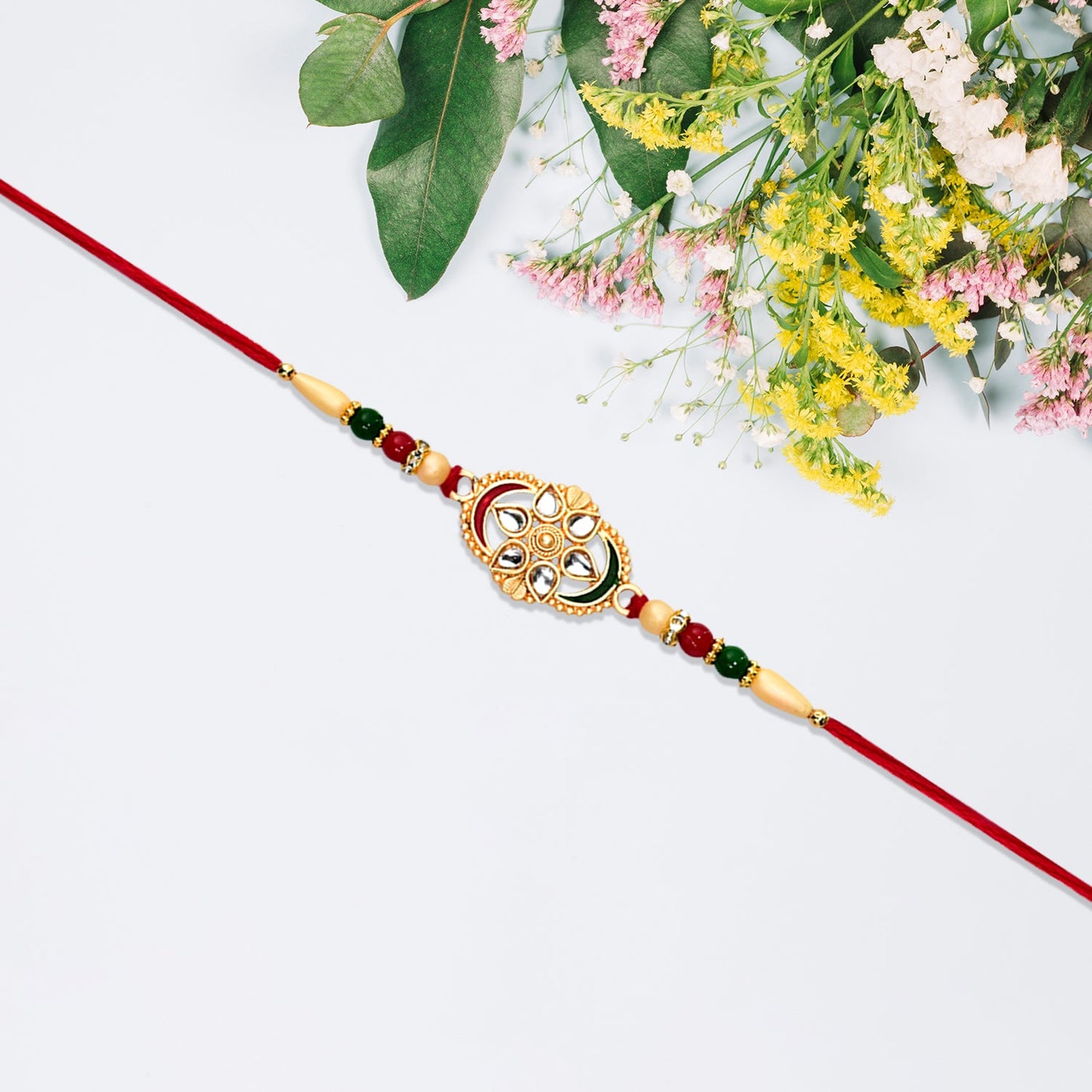Traditional Oval Rakhi with Kundan Work and Red-Green Beads