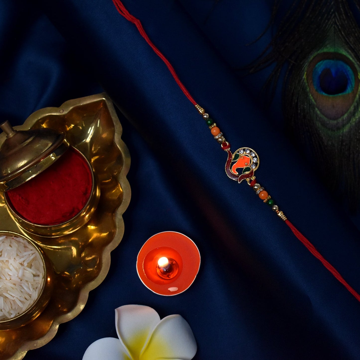 Golden Ganesha Rakhi with Red-Green Beads and Stone Detailing