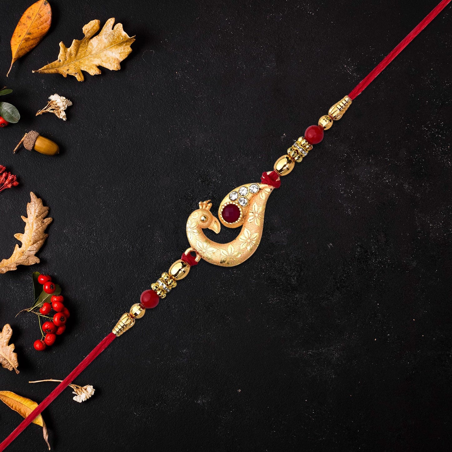Golden Peacock Feather Rakhi with Red Thread and Kundan Detailing