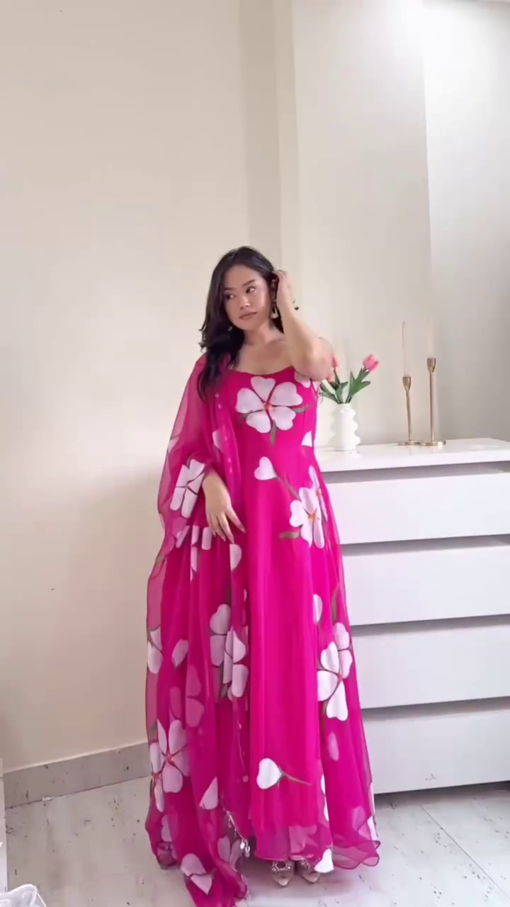 A vibrant pink flowy dress with large white floral prints, paired with a sheer matching dupatta, exuding a lively and feminine vibe. Perfect for festive or semi-formal occasions.