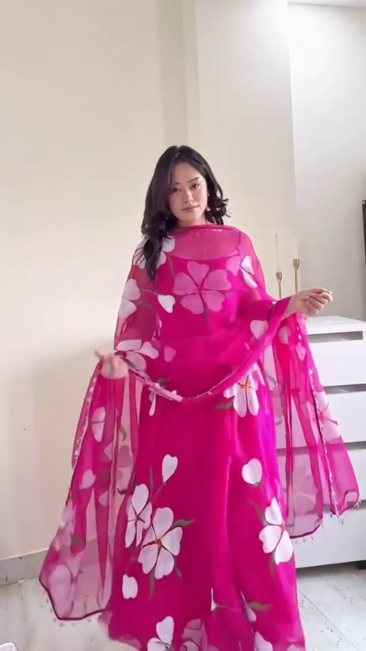 A vibrant pink flowy dress with large white floral prints, paired with a sheer matching dupatta, exuding a lively and feminine vibe. Perfect for festive or semi-formal occasions.