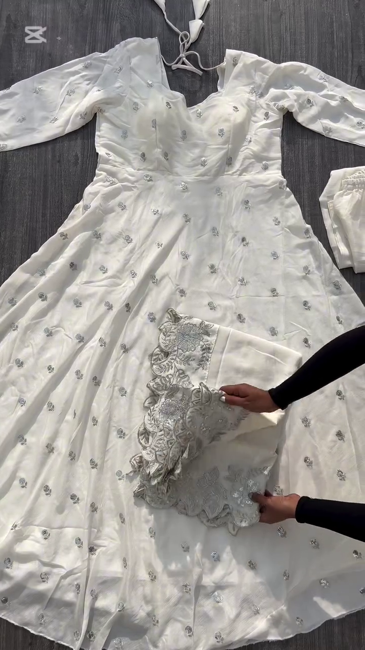 A beautiful white dress adorned with delicate silver embroidery, perfect for an elegant and sophisticated look. The intricate design along the hem adds a touch of charm to this graceful outfit.