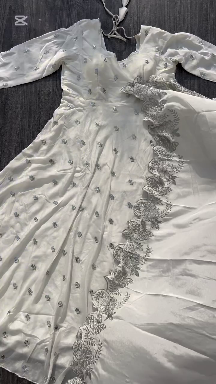 A beautiful white dress adorned with delicate silver embroidery, perfect for an elegant and sophisticated look. The intricate design along the hem adds a touch of charm to this graceful outfit.