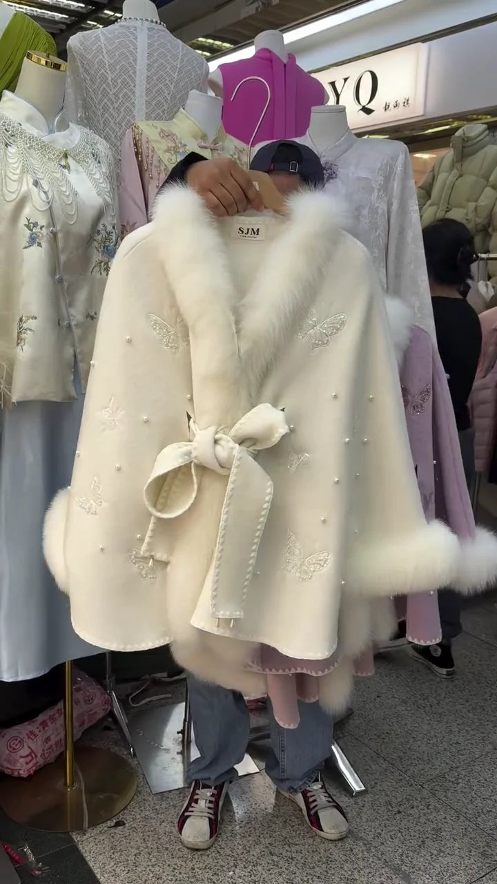 Luxurious Wool Blend Cape Coat with Plush Faux Fur Trimmed Collar and Hem, Featuring Delicate Embroidered Butterfly Appliqués, Faux Pearl Accents, and a Matching Self-Tie Waist Bow, Available in Elegant White and Soft Pink